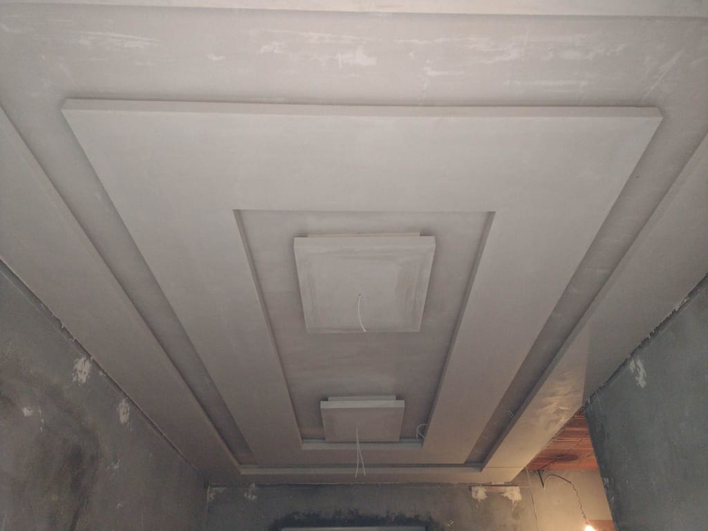 Faux plafond en plaques de plâtre vu du dessous : deux cadres en retrait emboîtés l'un dans l'autre et un caisson central prévu pour le point lumineux. Les joints sont poncés et la surface est prête à peindre.